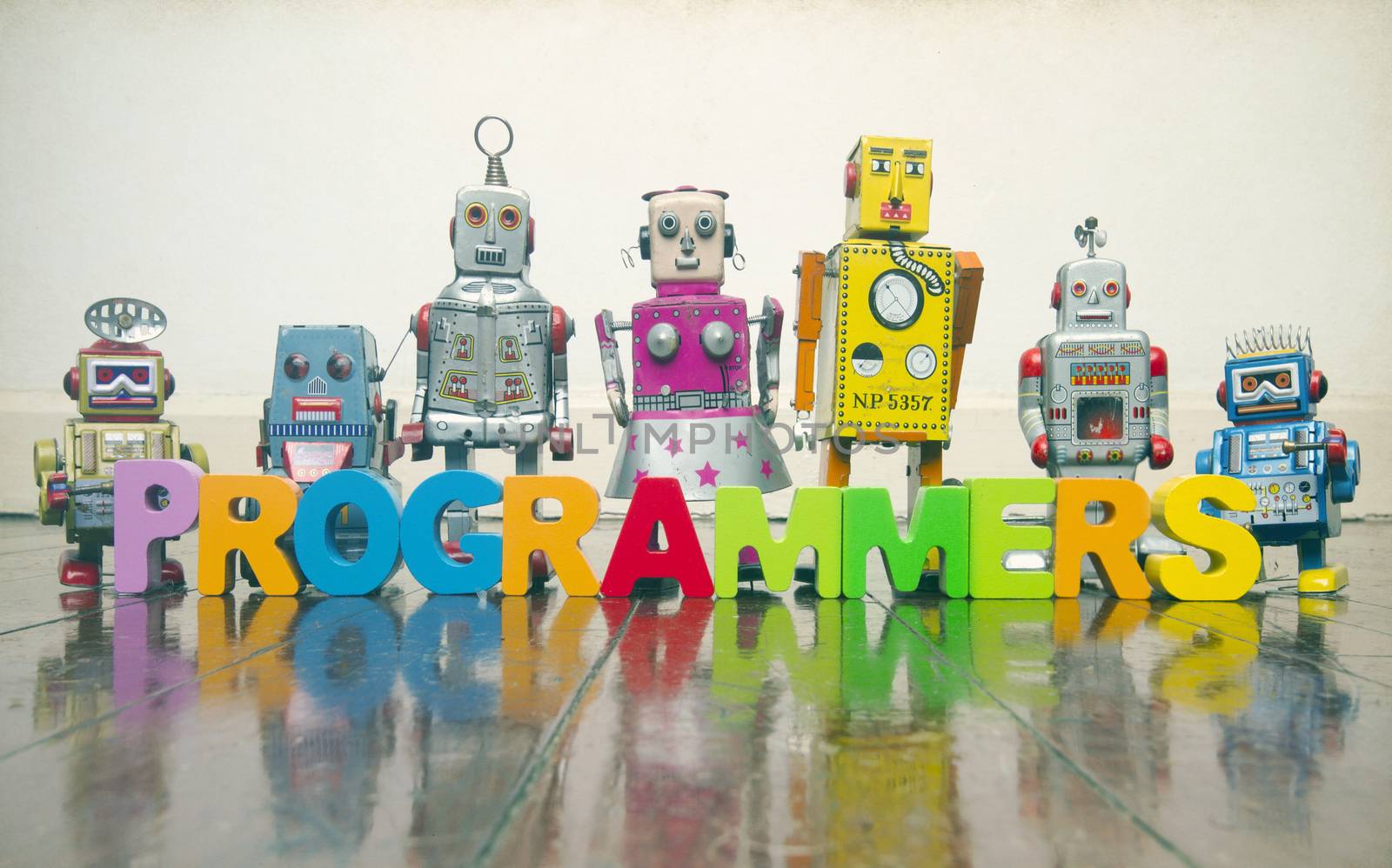 the word  PROGRAMMERS with wooden letters and retro toy robots   by davincidig