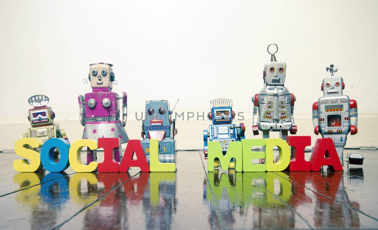 the words SOCIAL MEDIA   with rtro robot toys on a wooden floo by davincidig