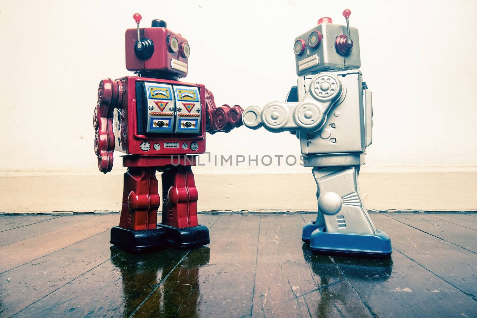 two vintage robot shake hands on a old wooden floor  toned image 