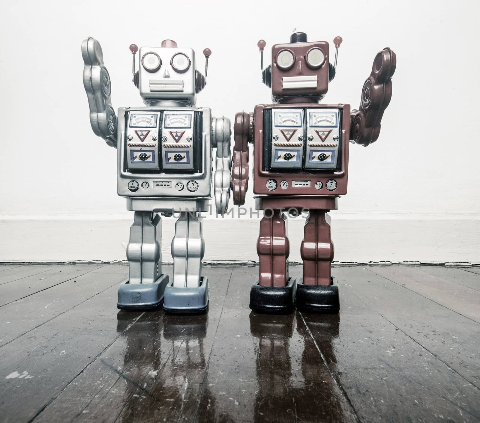 two vintage robots say hi  on a wooden floor toned image 