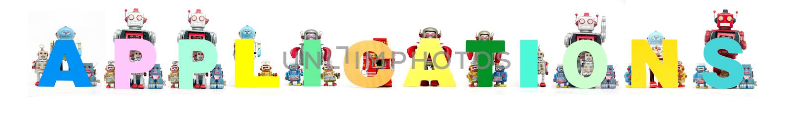 retro tin robot toys hold up the word APPLICATIONS isolated on white