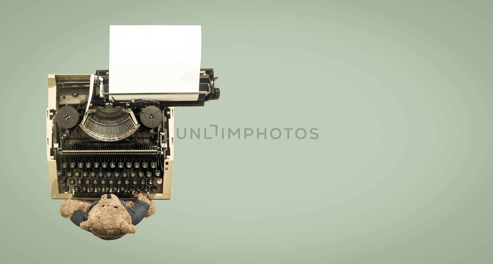 an old teddy bear at on a vintage typewriter from above toned green image