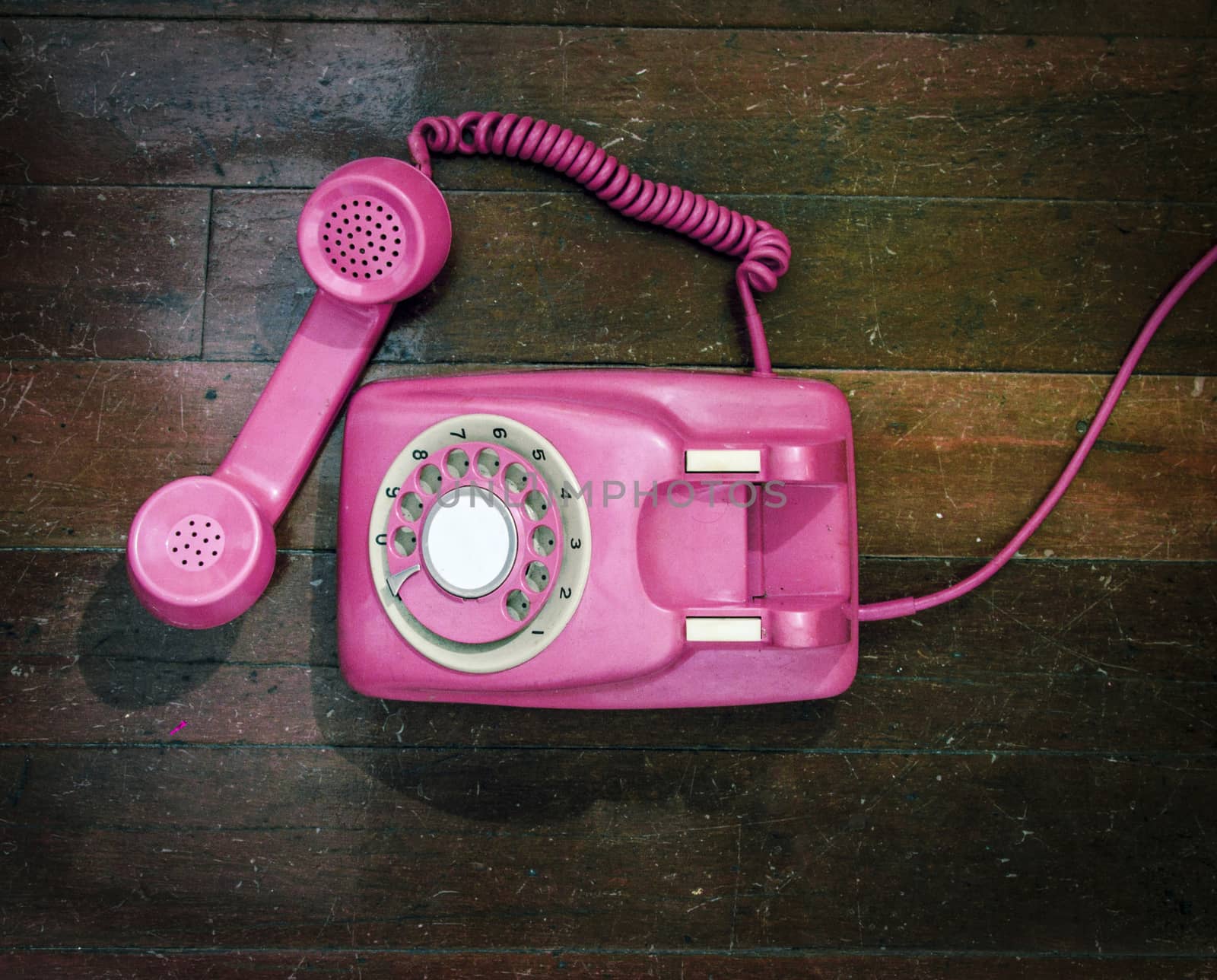 vintage pink phone on a old wooden floor from above 