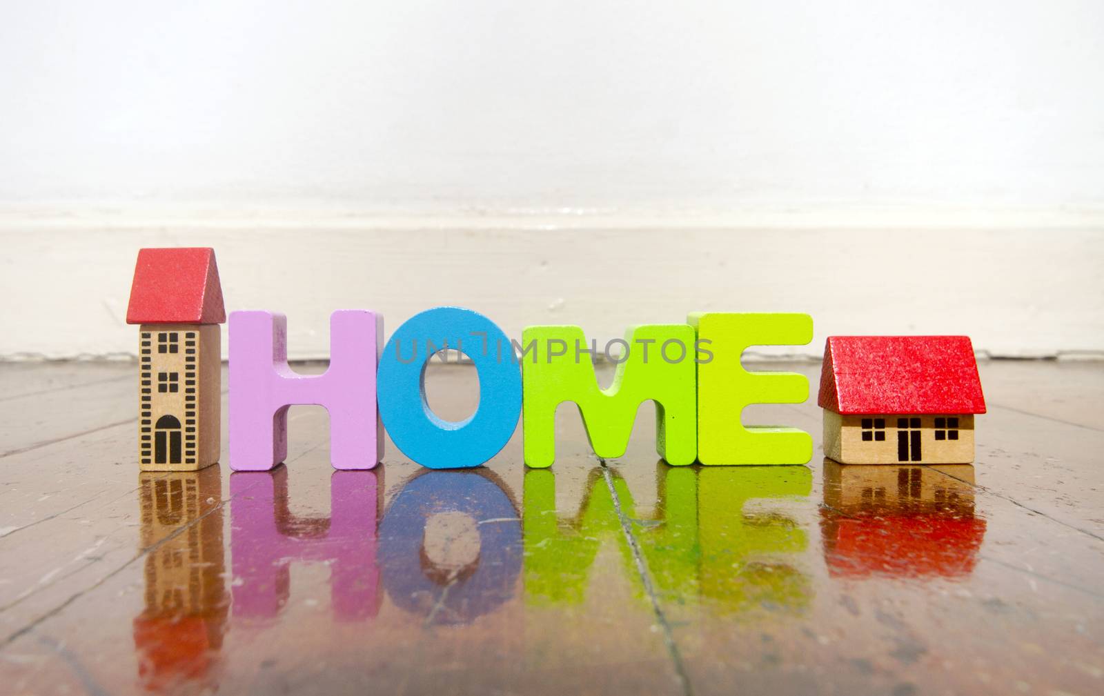 the word home with wooden letters on a wooden floor by davincidig