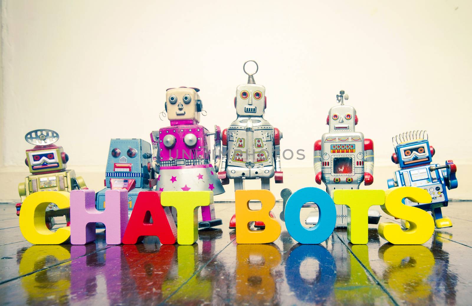 the words  CHAT BOTS  with wooden letters and retro toy robots   by davincidig