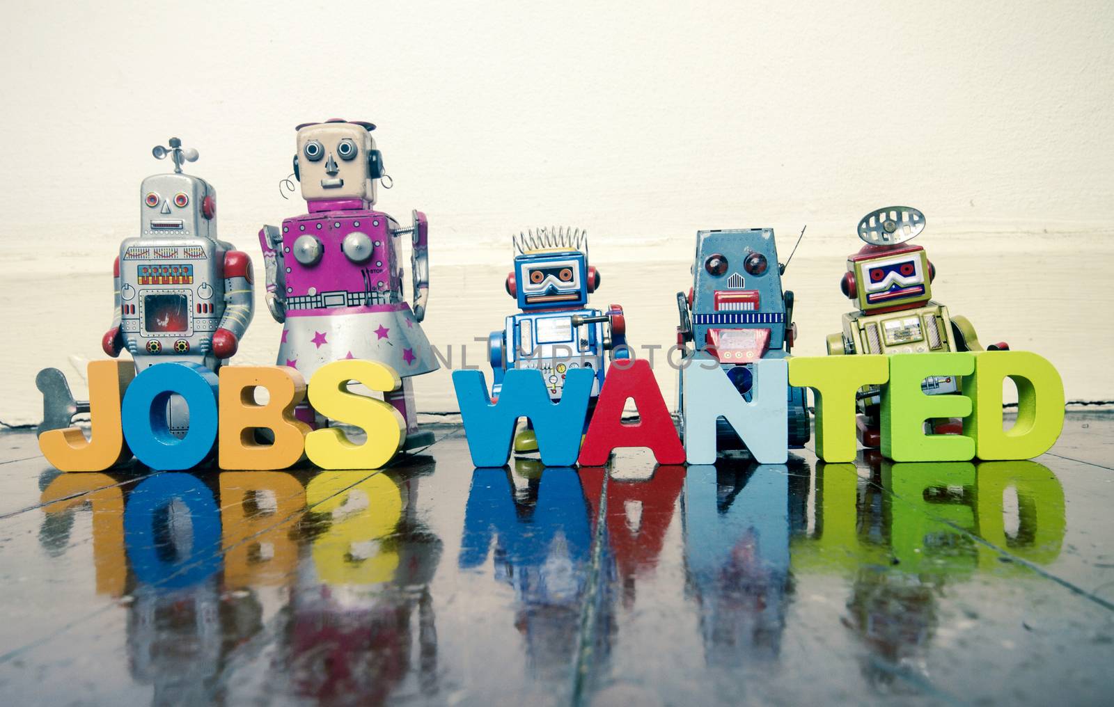 the words JOBS WANTED with wooden letters and robot toys on a wo by davincidig