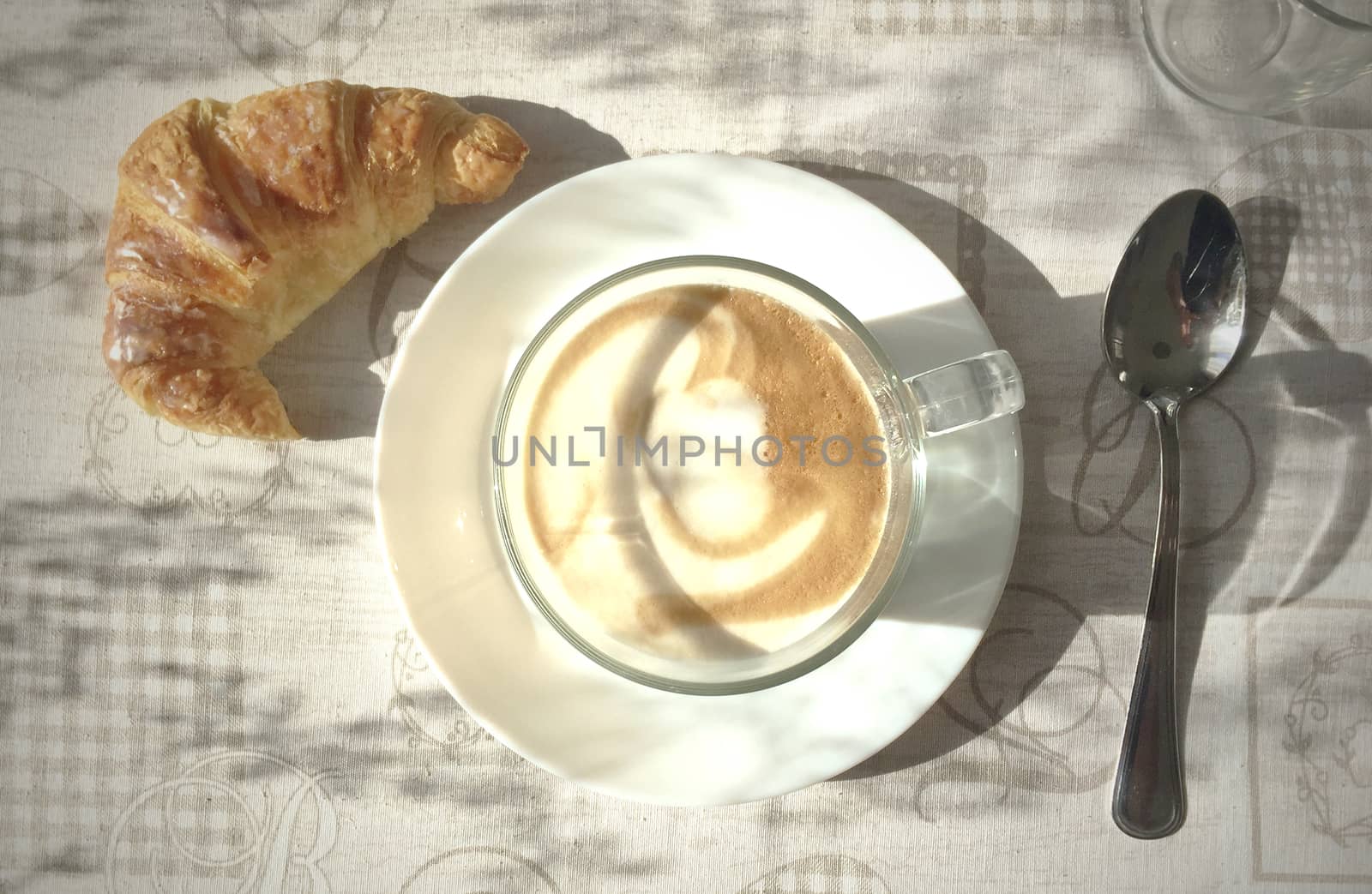 Aerial view of a foamy Cappuccino mug and a croissant