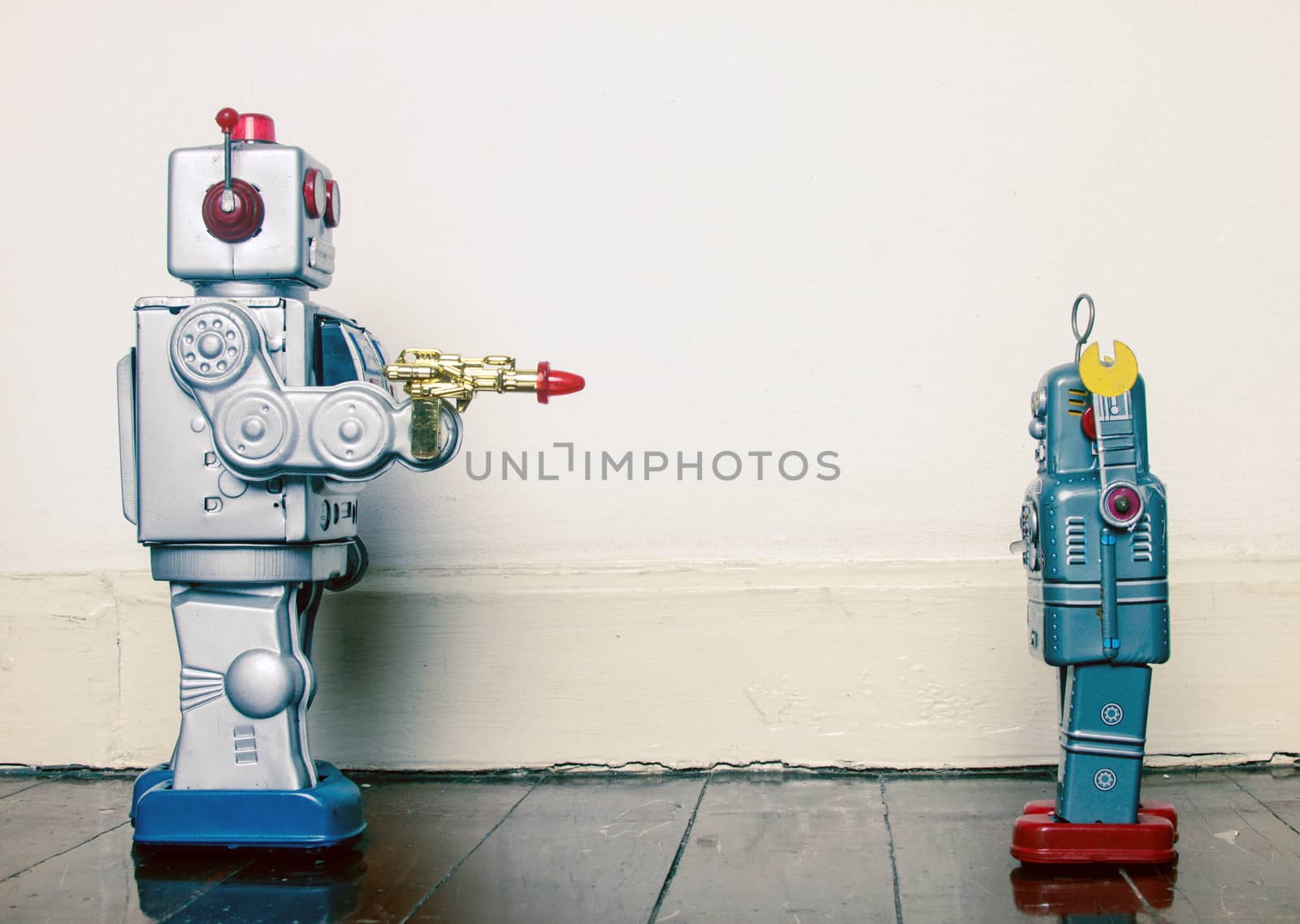 concept gun crime with retro toy robots on a wooden floor 