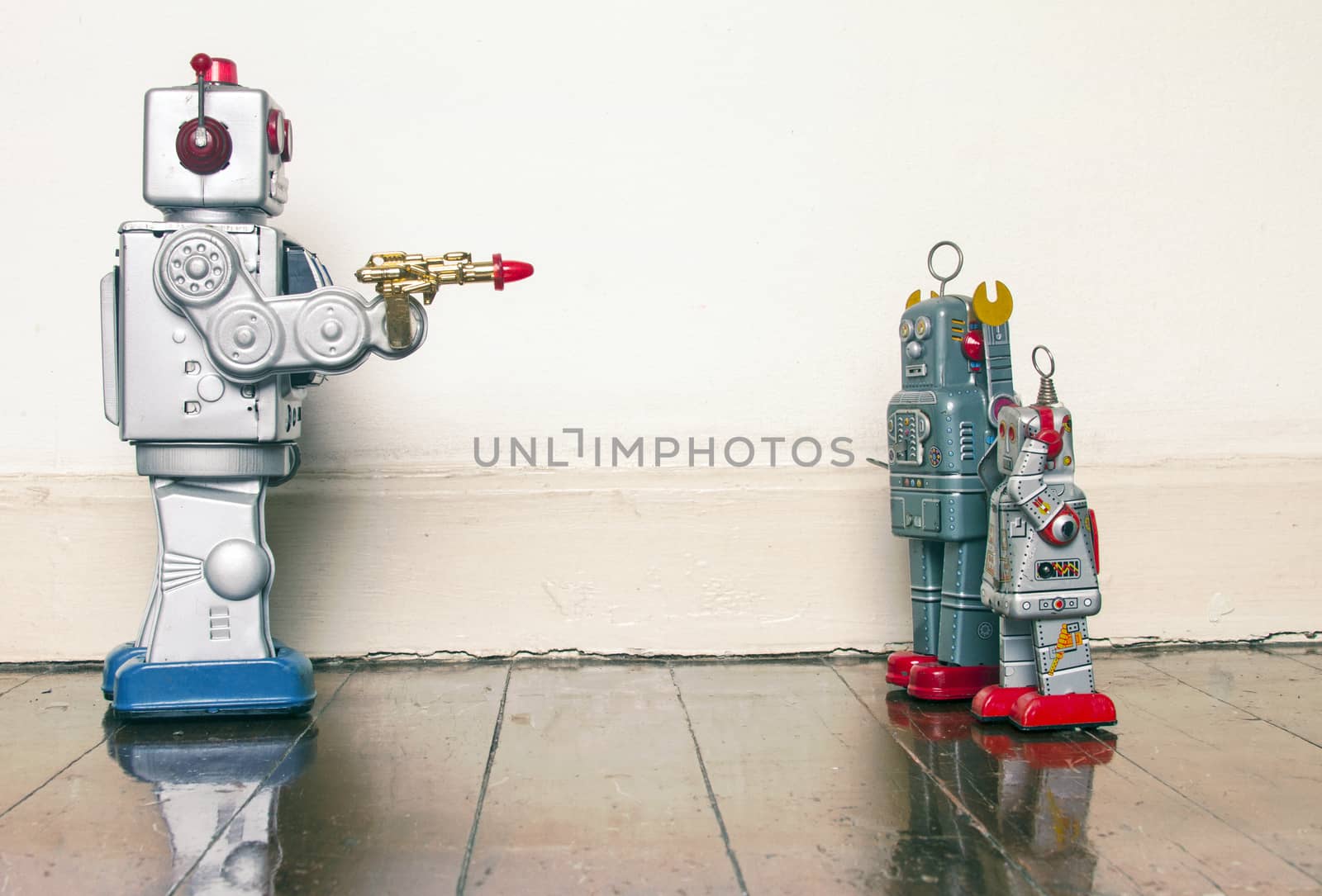 concept gun crime with retro toy robots on a wooden floor 