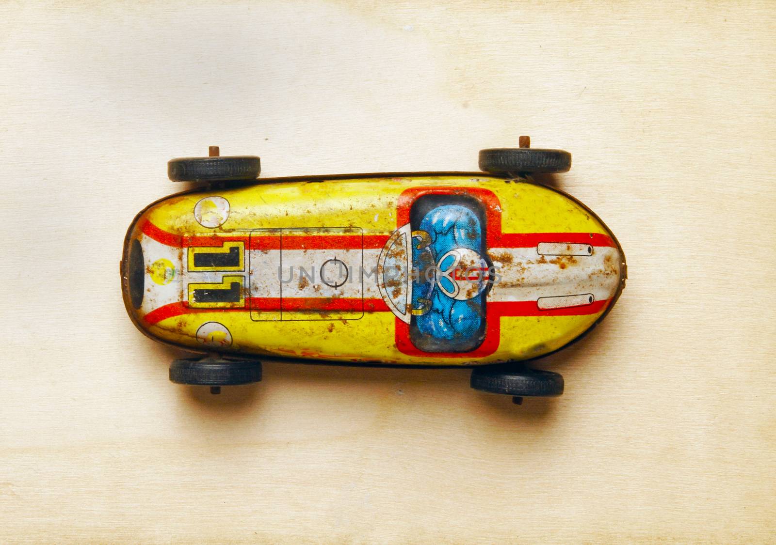 old tin toy  car on a wood background shot from above 