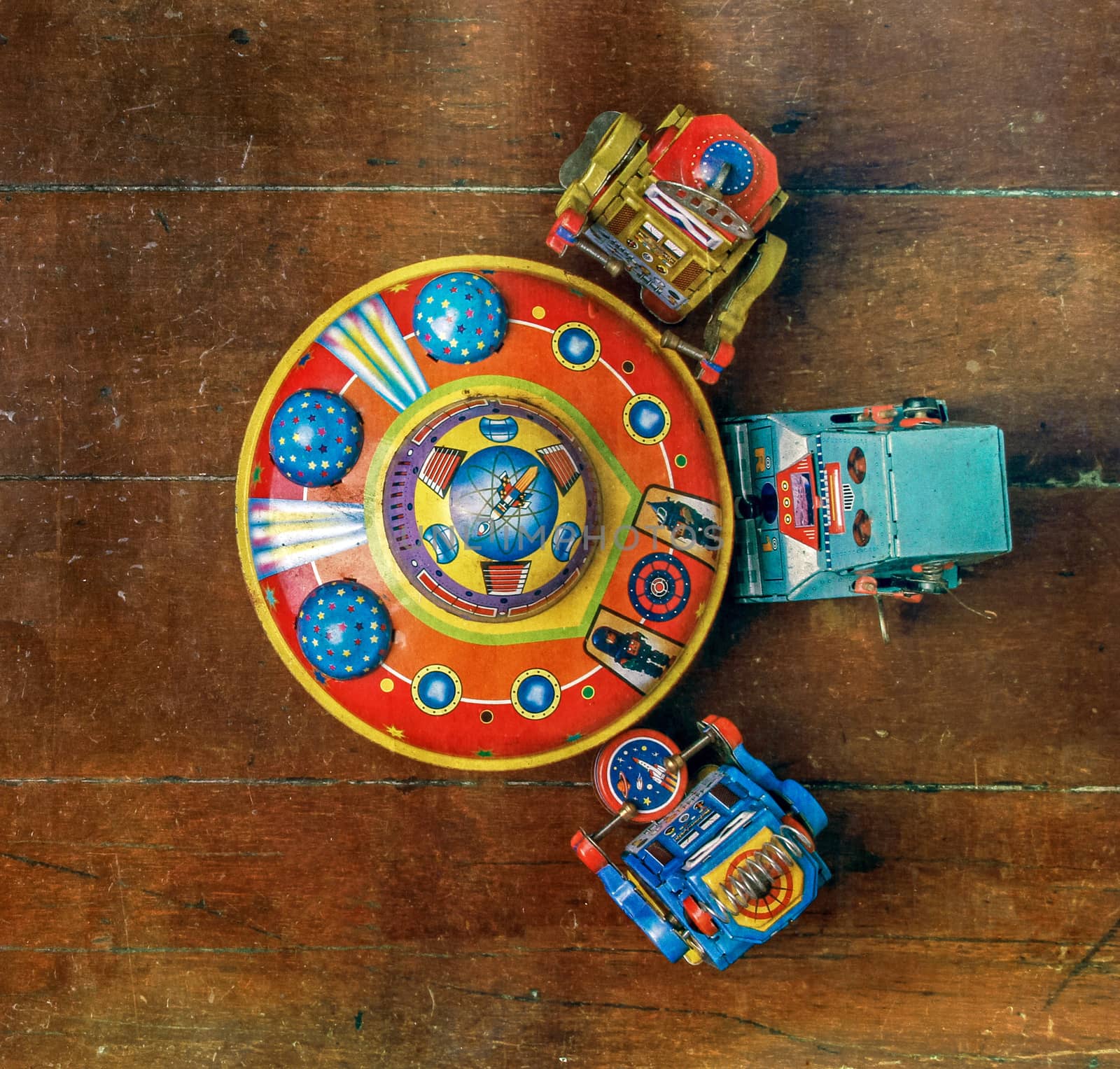 three rerto robots around a tin UFO  on a wooden floor  shot from above 