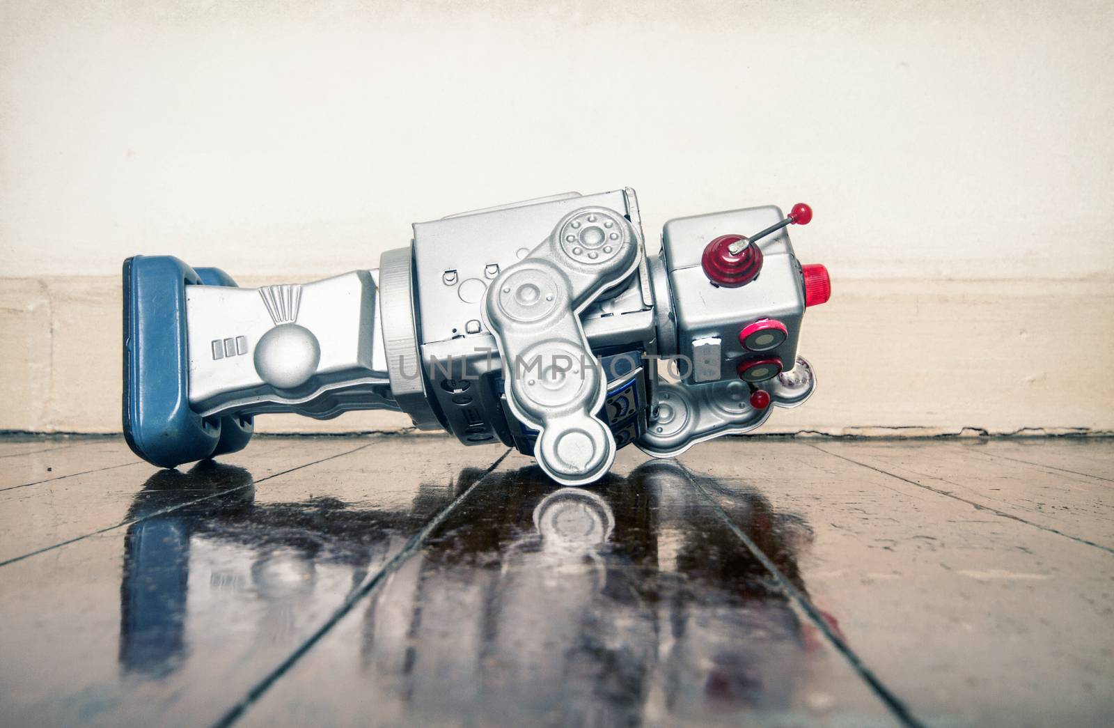 over worked retro silver robot facedown on old wooden floor with reflection