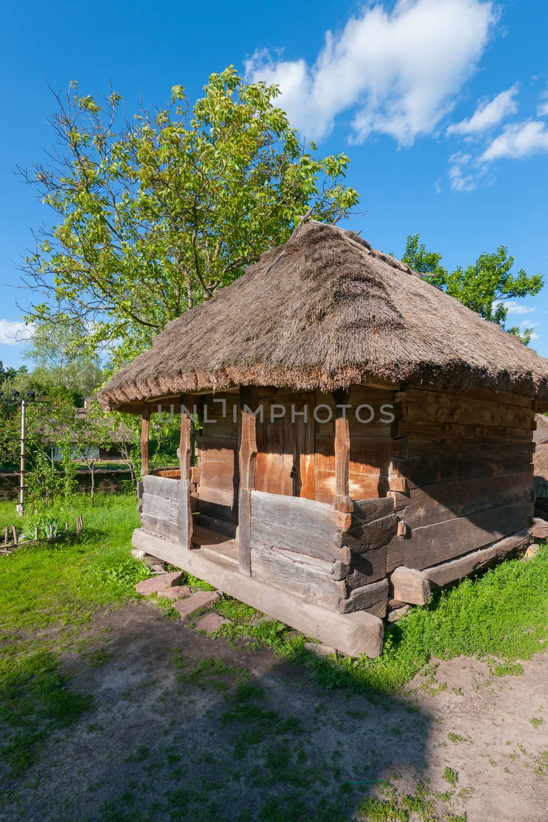 An old wooden house with a thatched roof with walls that have been decayed by time and the entrance door from the boards.