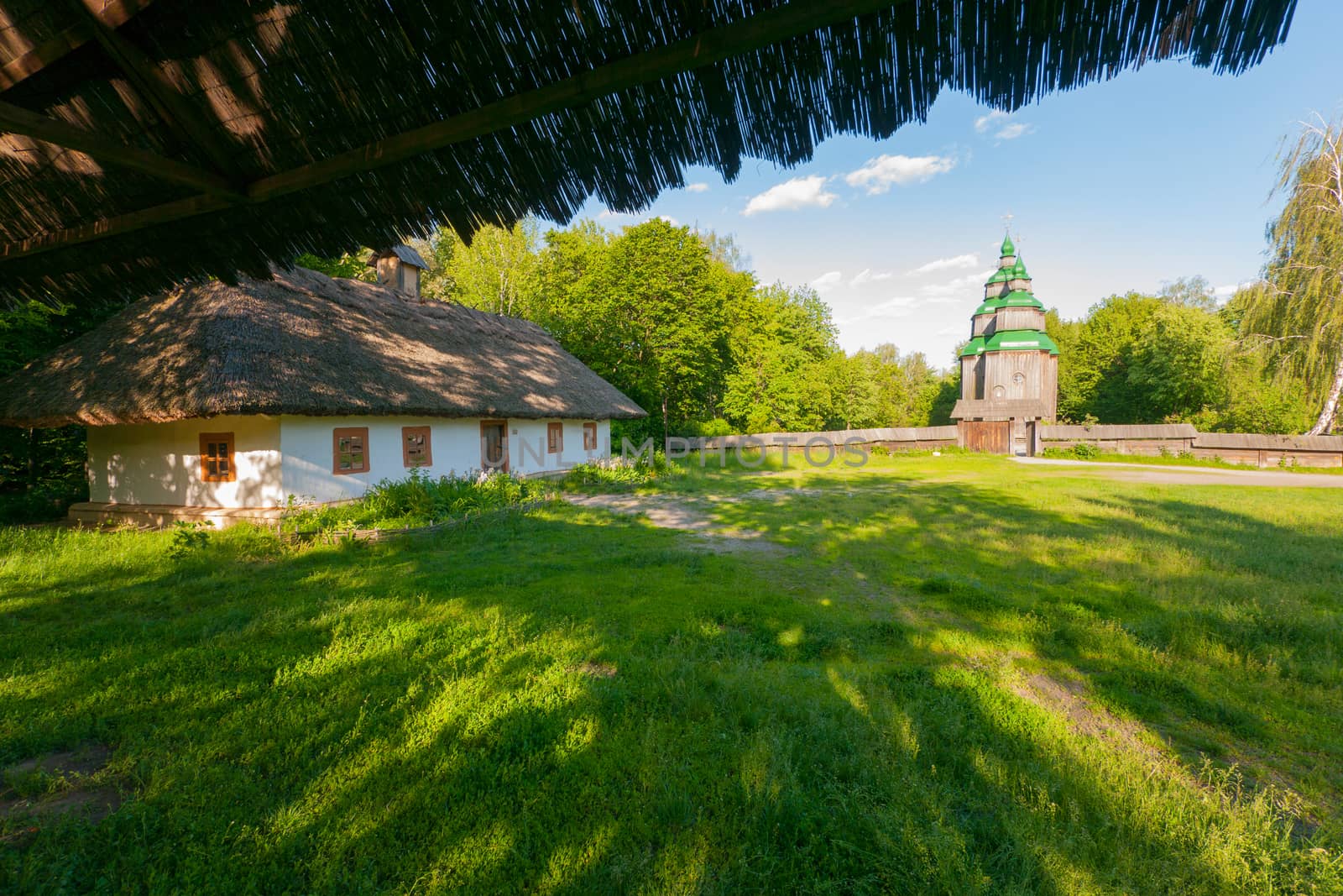 A large old Ukrainian hut on the background of a wooden church in the distance