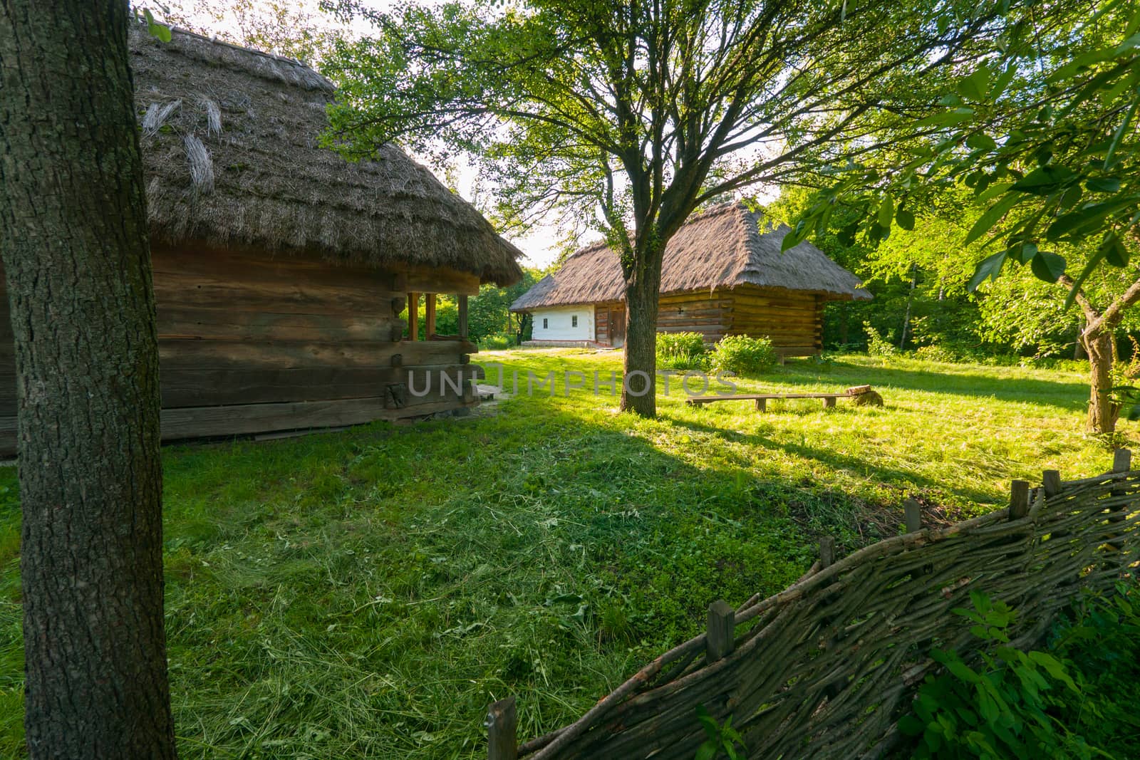 Decorative wicker fence on the background of old authentic Ukrainian houses with thatched roof