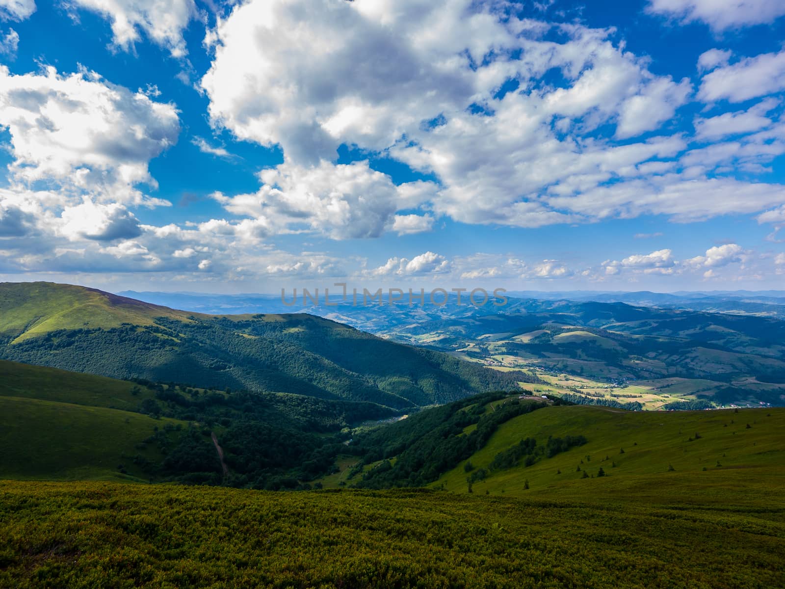 Beautiful big green mountain valley against a blue sky with white clouds