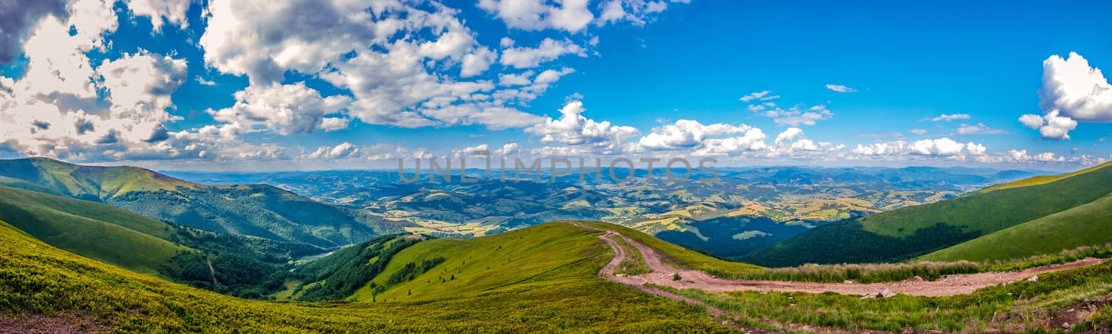 Panoramic view of green hills with mountains, large valleys and blue sky with white clouds on it by Adamchuk