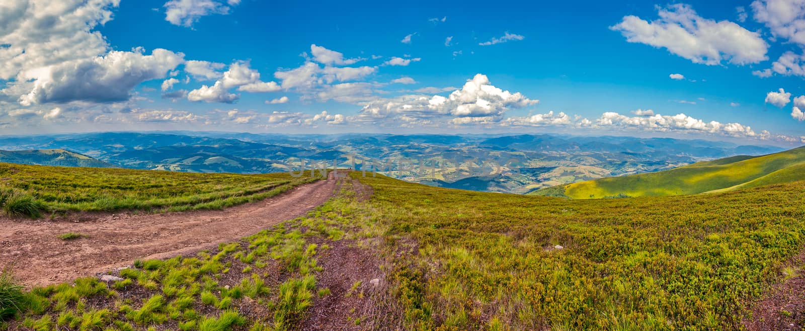 Magnificent panorama of the mountains stretching to the very horizon line and slowly floating above them clouds in the blue sky.