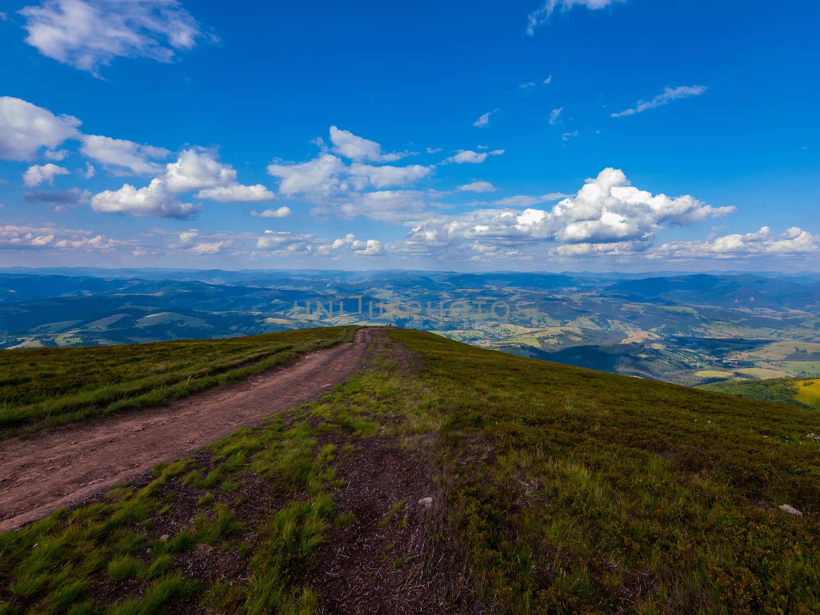 A boundless road in the mountains and quietly floating clouds above it in the sky