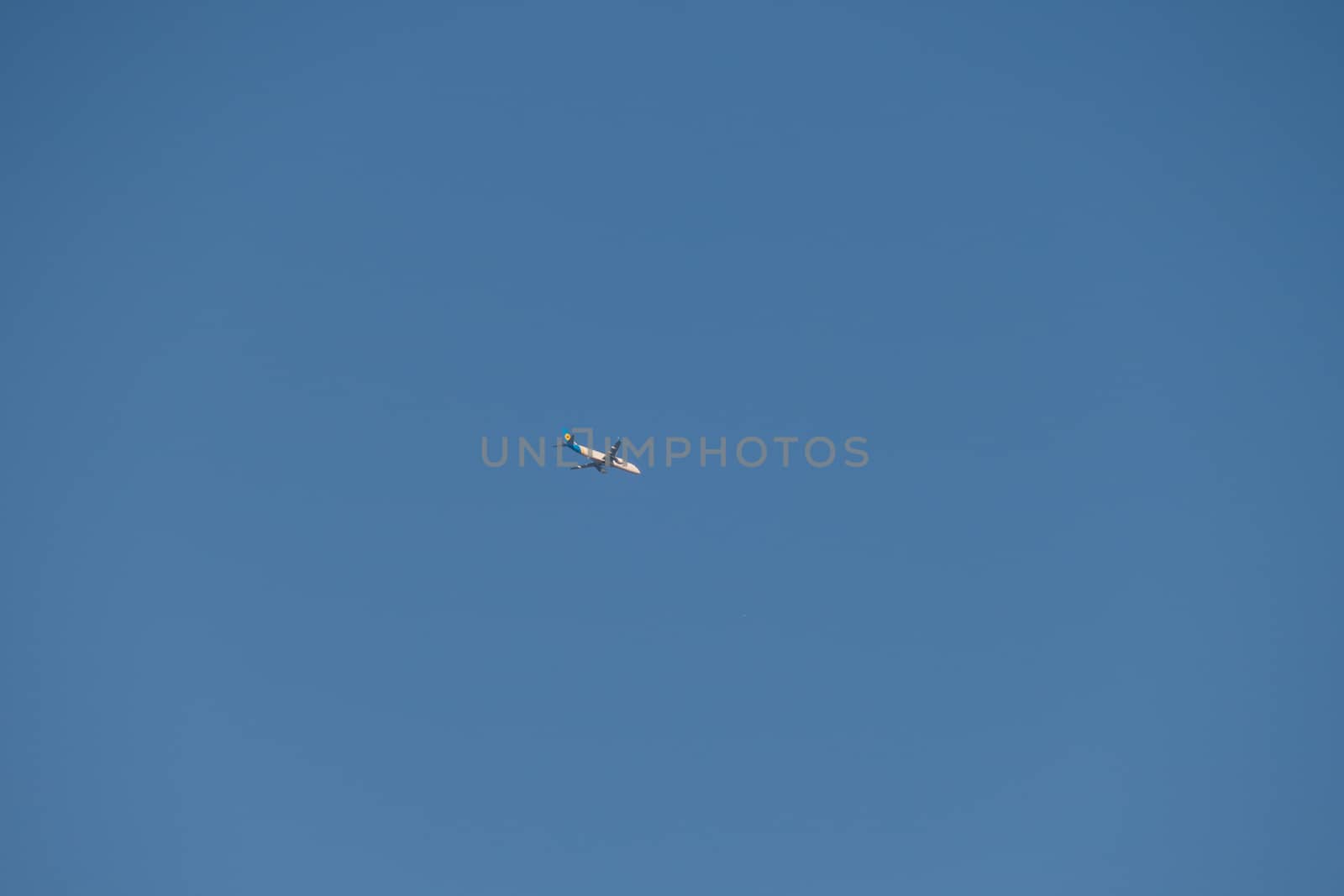 The white plane runs high in the blue sky without any clouds