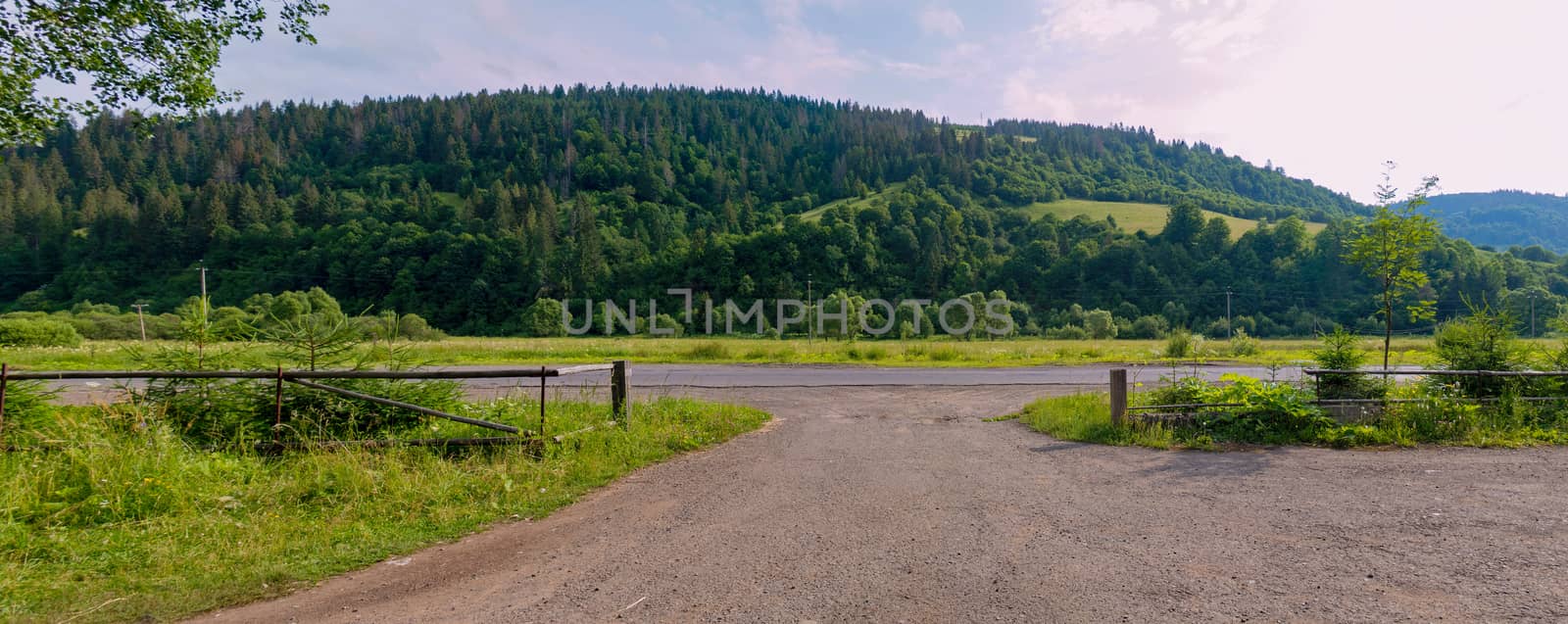 Extensive country road in the background of a mountain with green trees