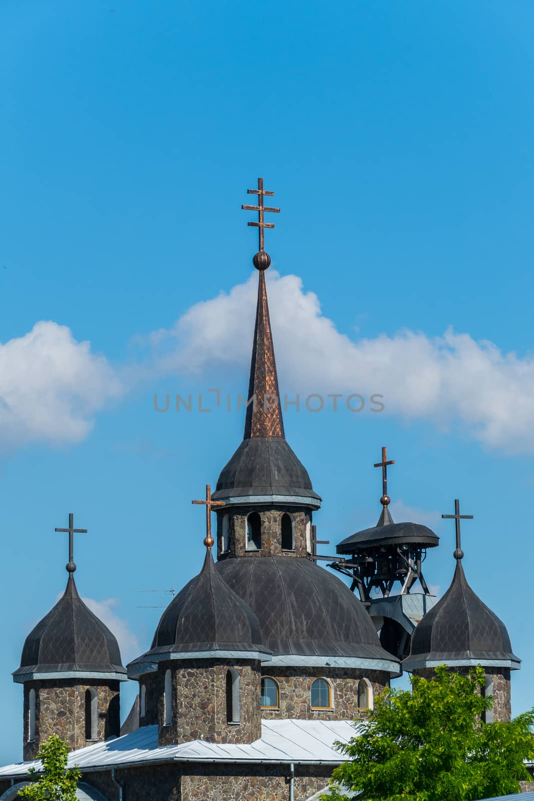 Ancient church with black domes against the blue sky. Made of brown stone. The contrast of color is striking
