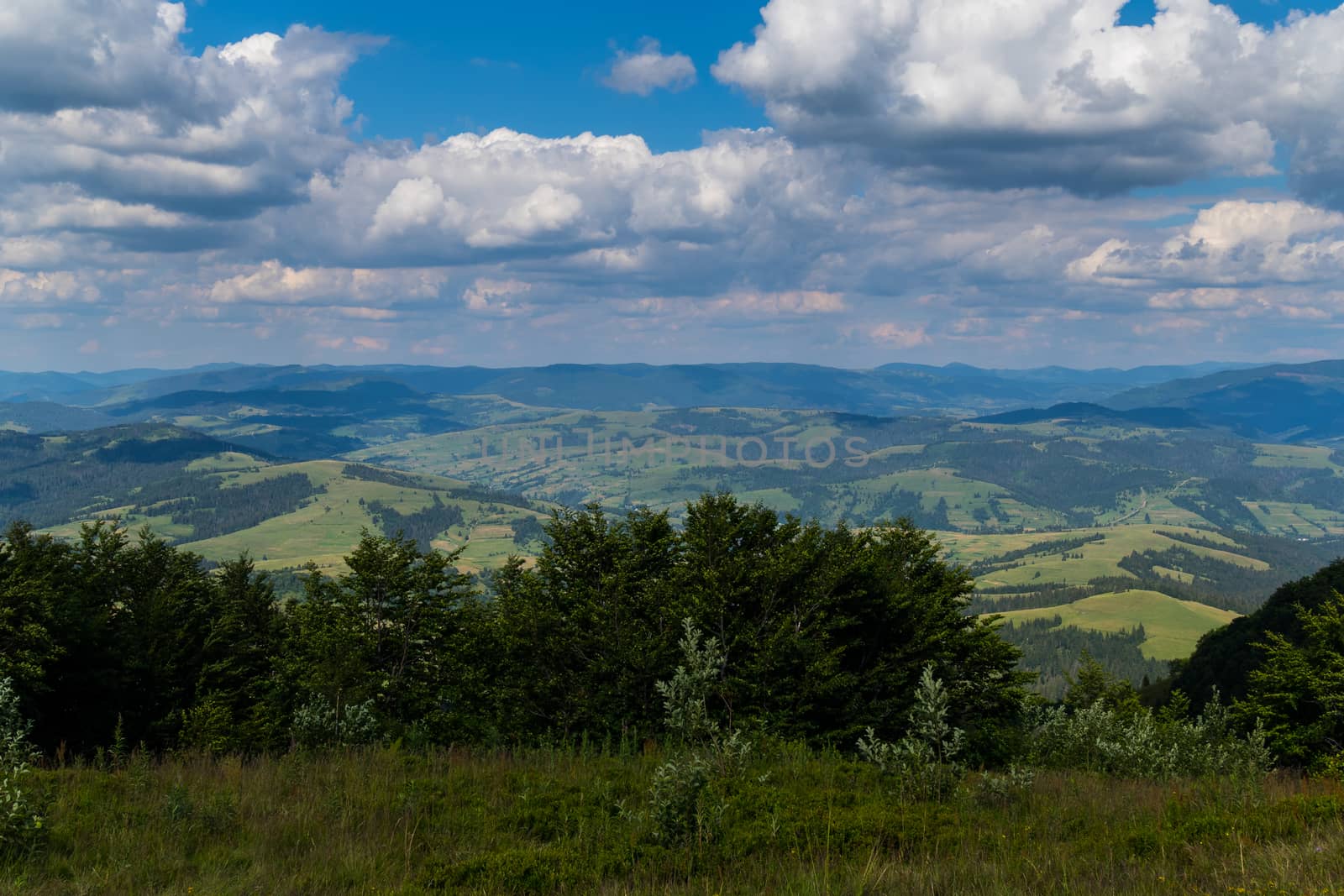 Dense clouds obscure almost all the sky slowly sailing over the mountain valleys and hills. by Adamchuk