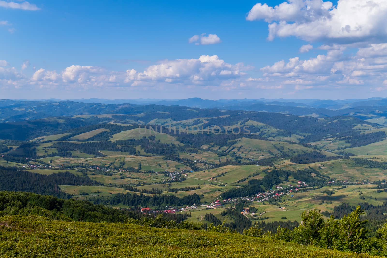 Slender rows of rural houses lying in green mountain valleys. From the top of the slope seeming quite small.