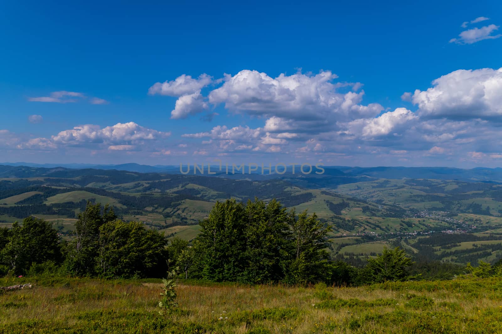 Landscape of mountain peaks and valleys with houses below. Beautiful greenery of trees and grasses and a beautiful purity of heavenly heights.