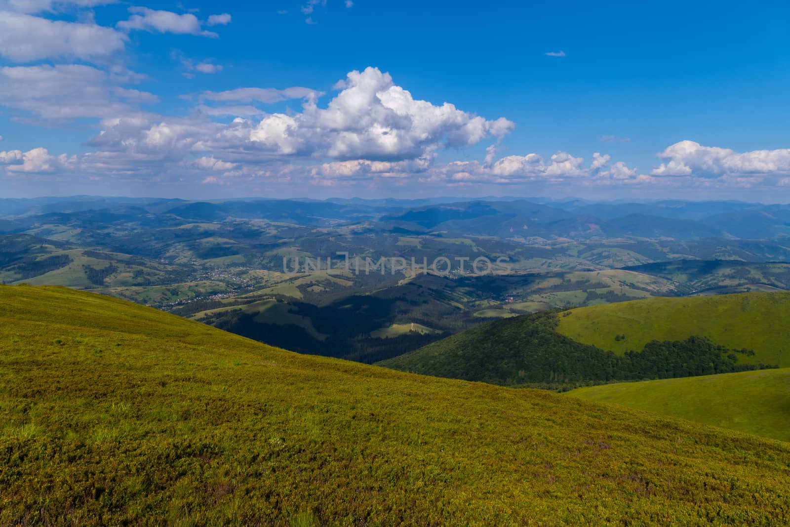 The green grassy top of the mountain with a beautiful view around for many kilometers up to the horizon line.