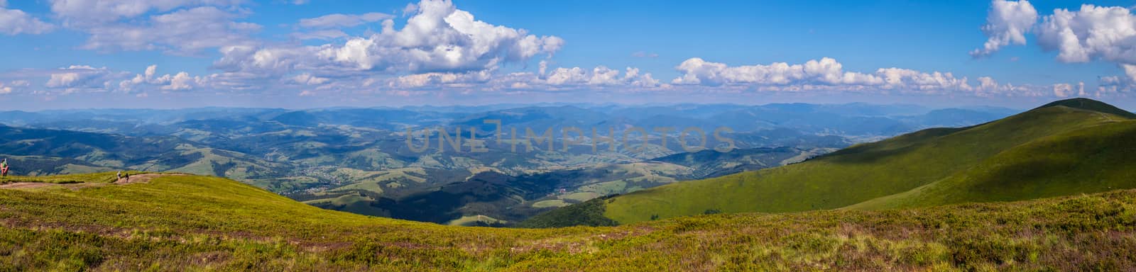 A majestic panorama of green mountain peaks stretching to the horizon line by Adamchuk