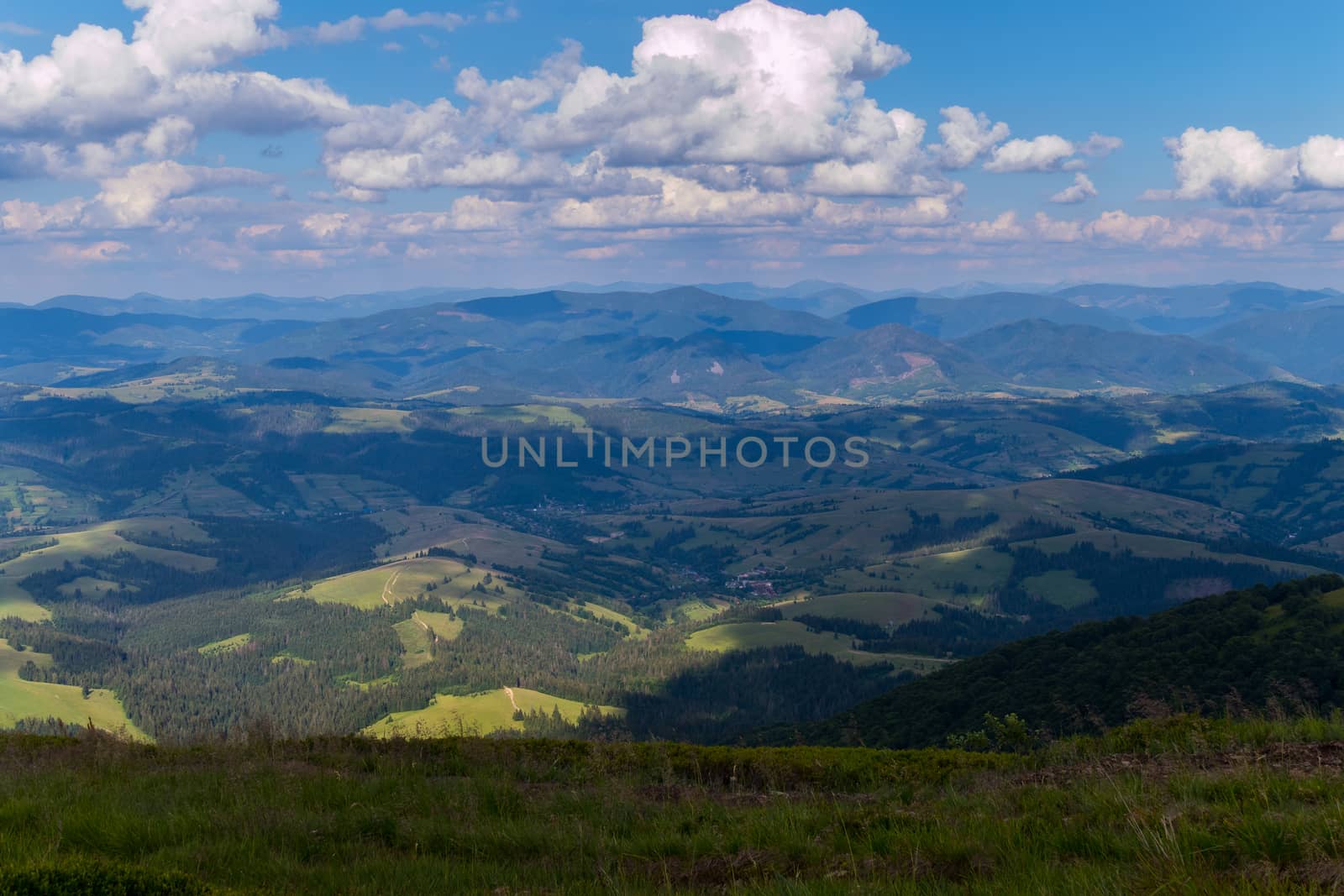 View from the top of the mountain to the forest glades, fields and village in the bright summer sun