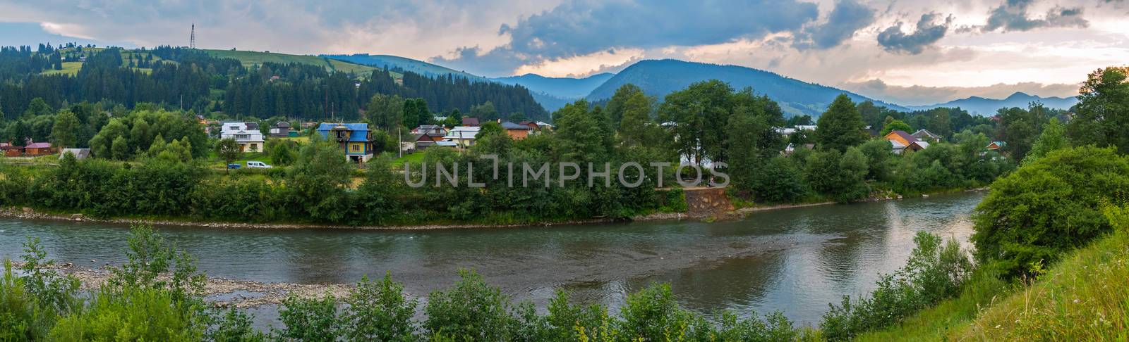 a magnificent panorama of the village lying on the river bank and dense clouds in the sky floating above it by Adamchuk