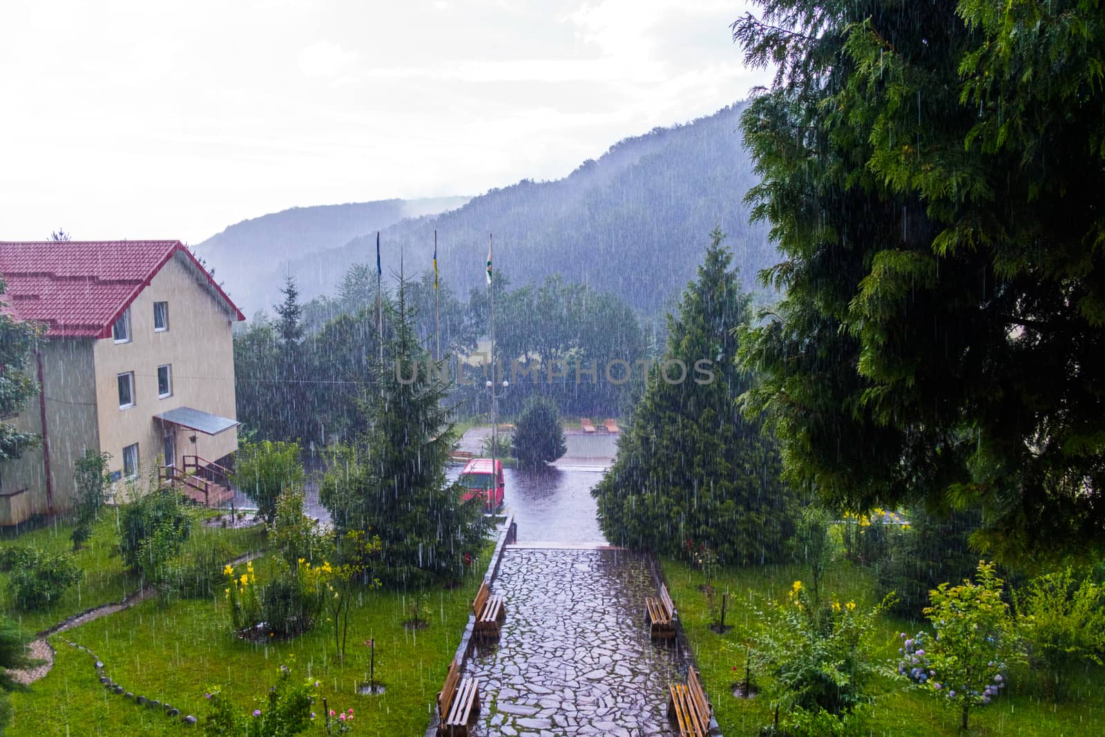 Large drops of rain fall on the house with a small park around it