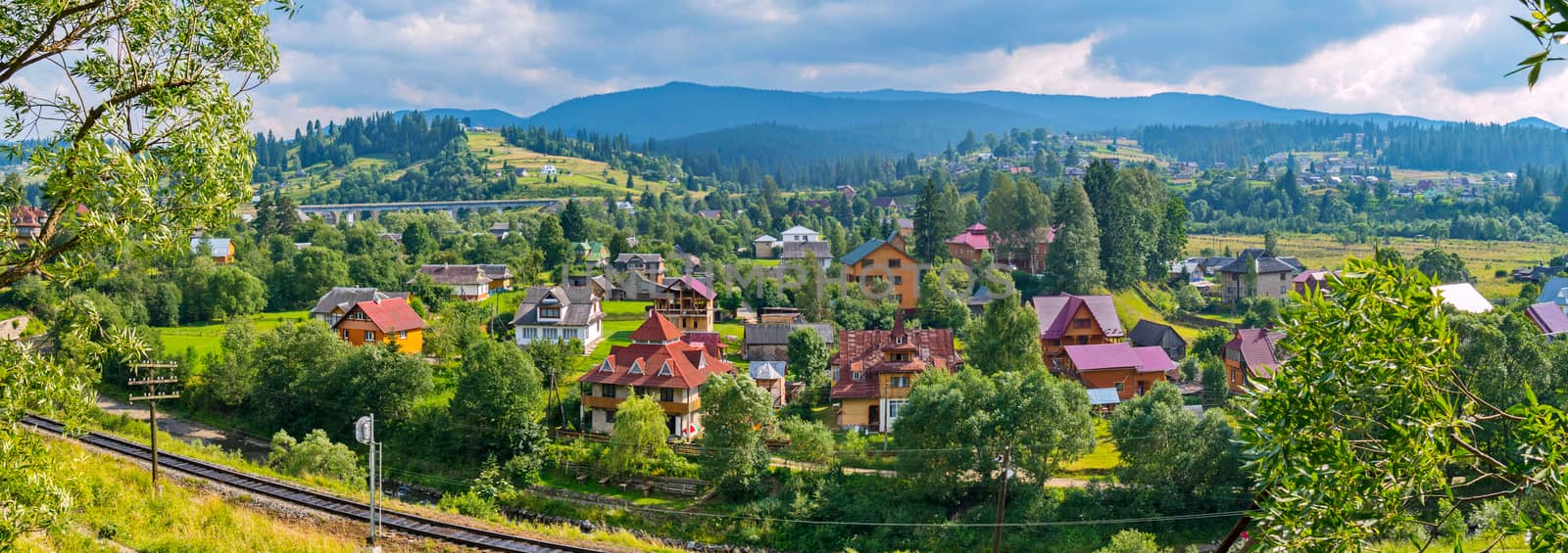 beautiful panorama of the Transcarpathian village with elite houses near the railway on the background of the blue mountains by Adamchuk