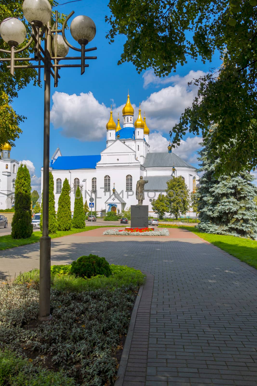 Monument to the leader against the background of a large beautiful white church with golden domes