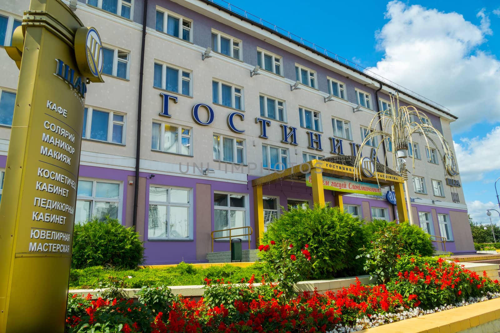 The facade of the hotel with a beautiful canopy and bright flowers in the flower garden in front of its entrance