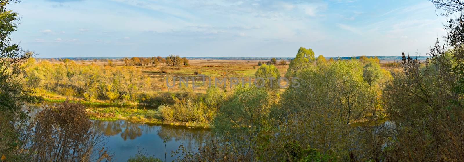 A beautiful autumn landscape with trees, a river and a field. When the hike is still warm, everything is already prepared for winter
