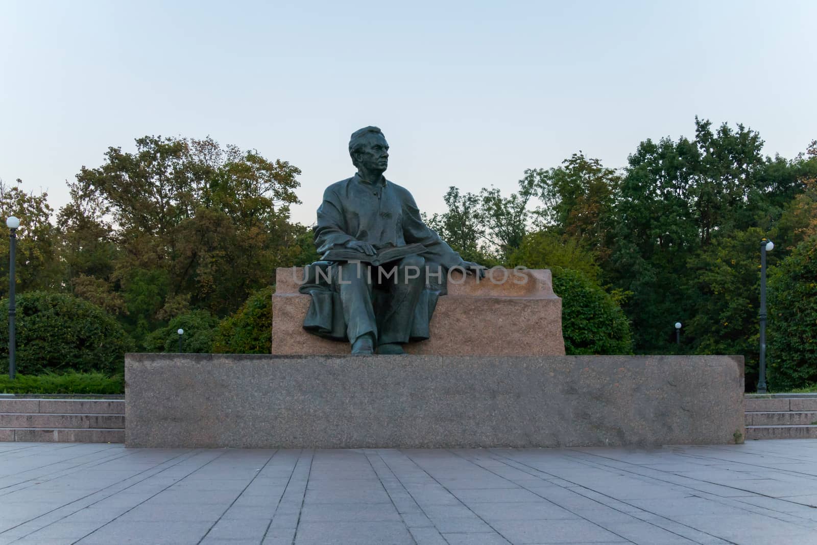 sculpture of a wise man sitting with an open book located on a pedestal in the park