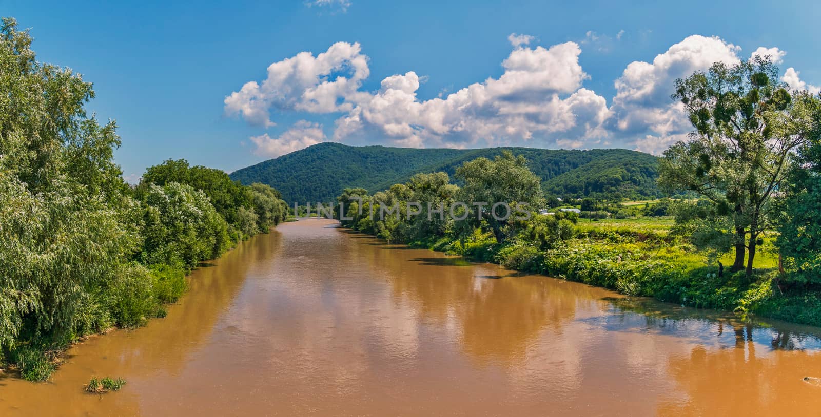 The river with water of color of sand flowing away to a mountain slope