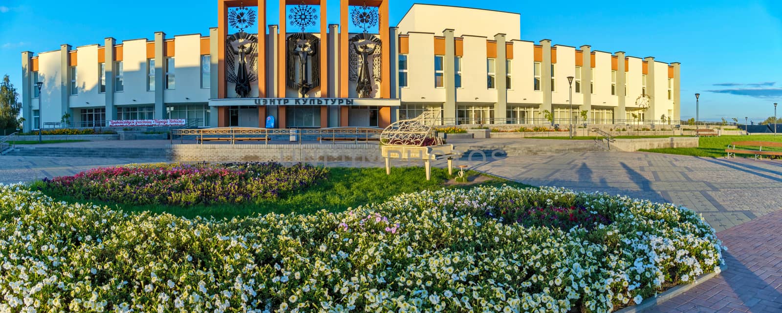 Beautiful, large building of the palace of culture. In front of him is a flower bed with a sculpture in the form of a piano by Adamchuk