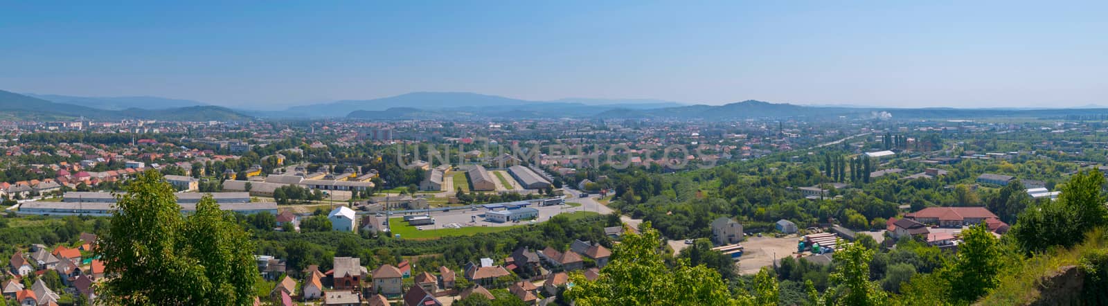 a magnificent panorama of the city with a beautiful nature lying in a green mountain valley by Adamchuk