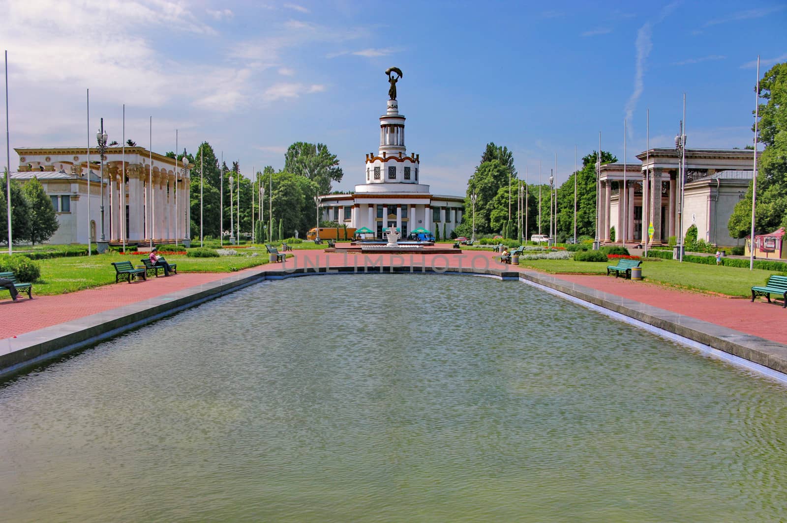 a large pool in the city on the background of a monument and installed benches to rest around it