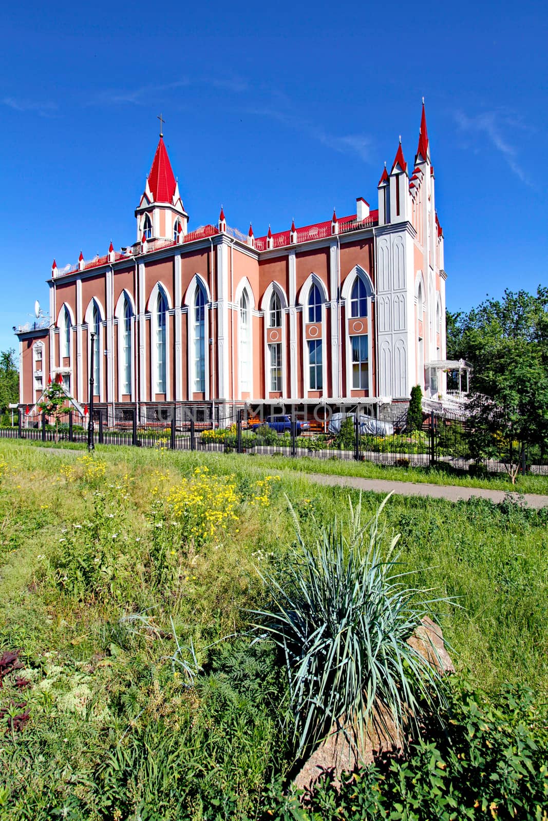 Flower bed with decorative flowers and shrubs on the background of a temple with a red acute-angled roof