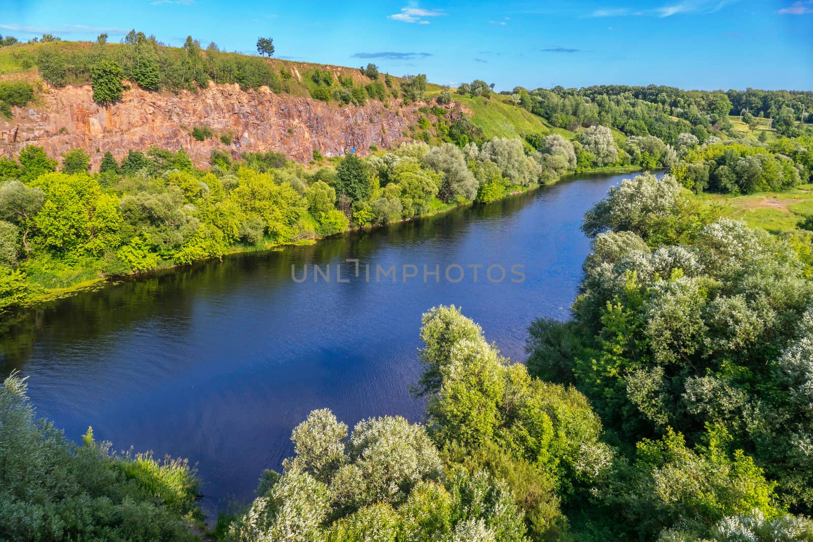 River bay with clear blue water on a background of rocky mountain and green plantations