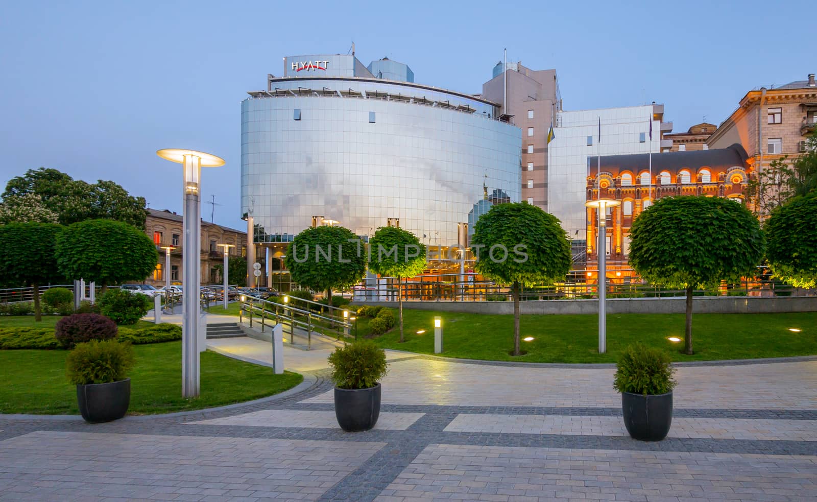 High modern building of the hotel with transparent windows on the background of the green park zone