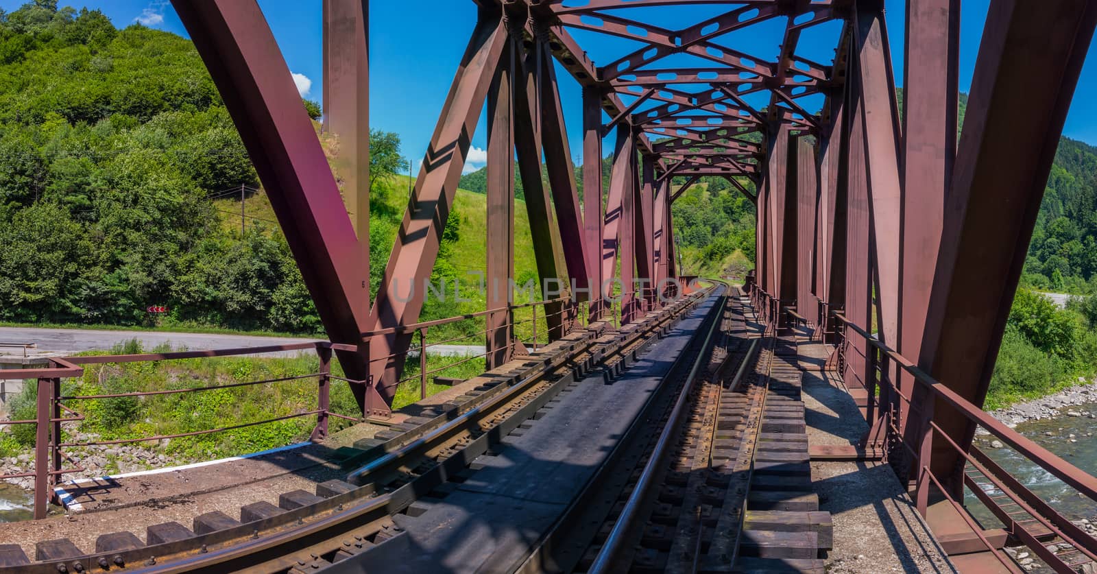 a railway bridge in a mountainous area and a small stream running beneath it