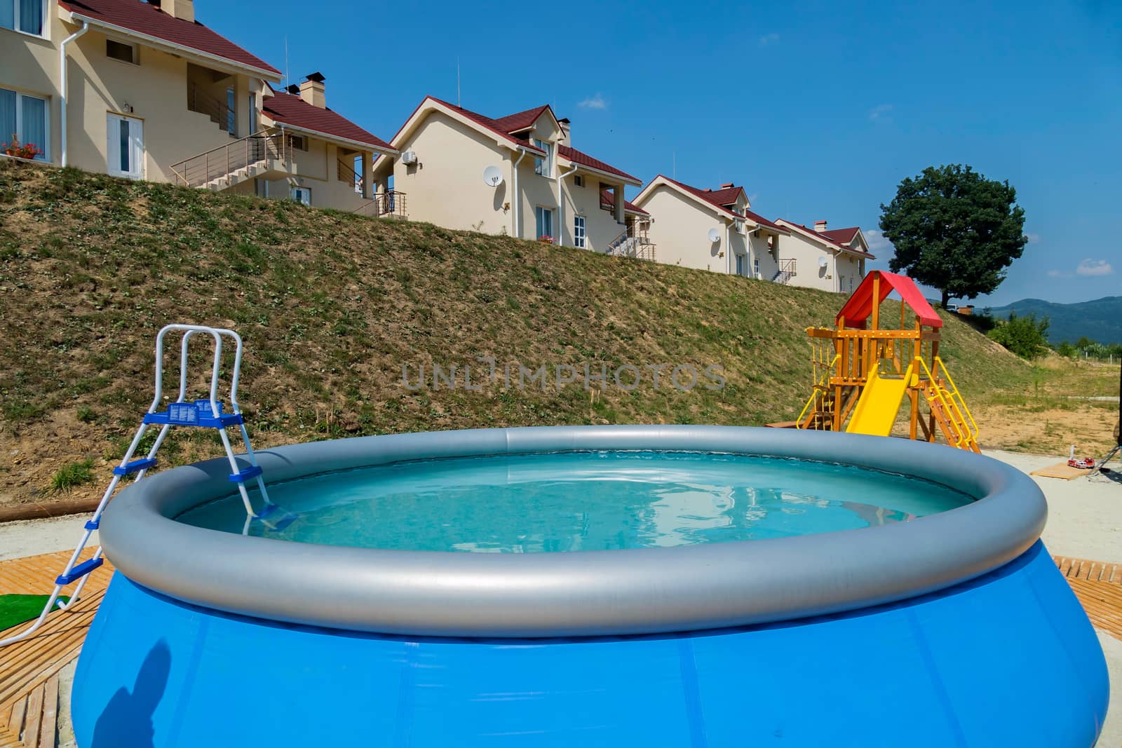 A ladder in a small basin in the form of a bowl with clear blue water. Standing next to the playground and holiday houses.