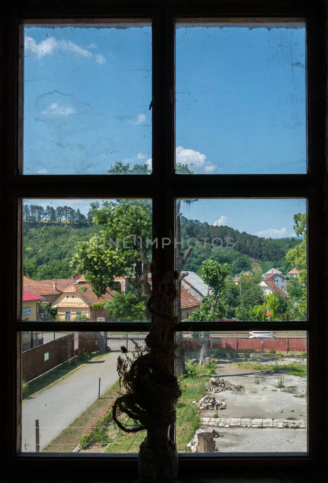 dried flowers on window sills with windows overlooking the country houses near the hill
