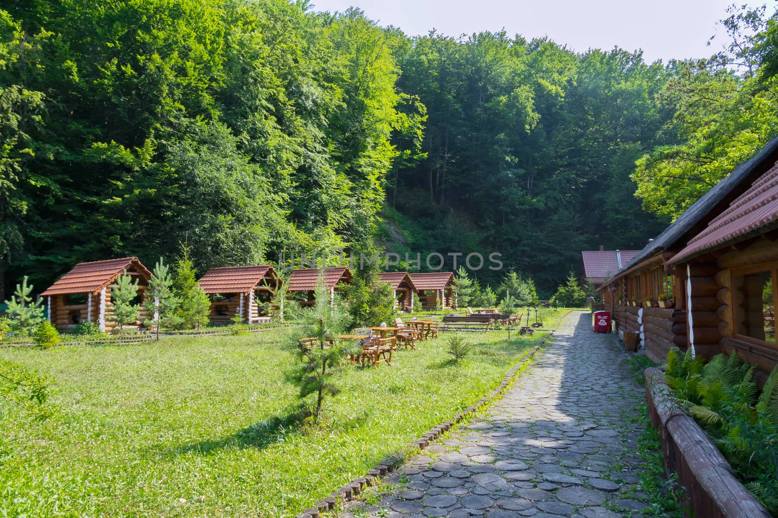 a recreation area and a picnic area with gazebos and houses of a wooden beam in a green coniferous forest
